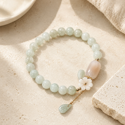 Shell Flower Jade Water Drop Bracelet on a warm ivory stone surface.