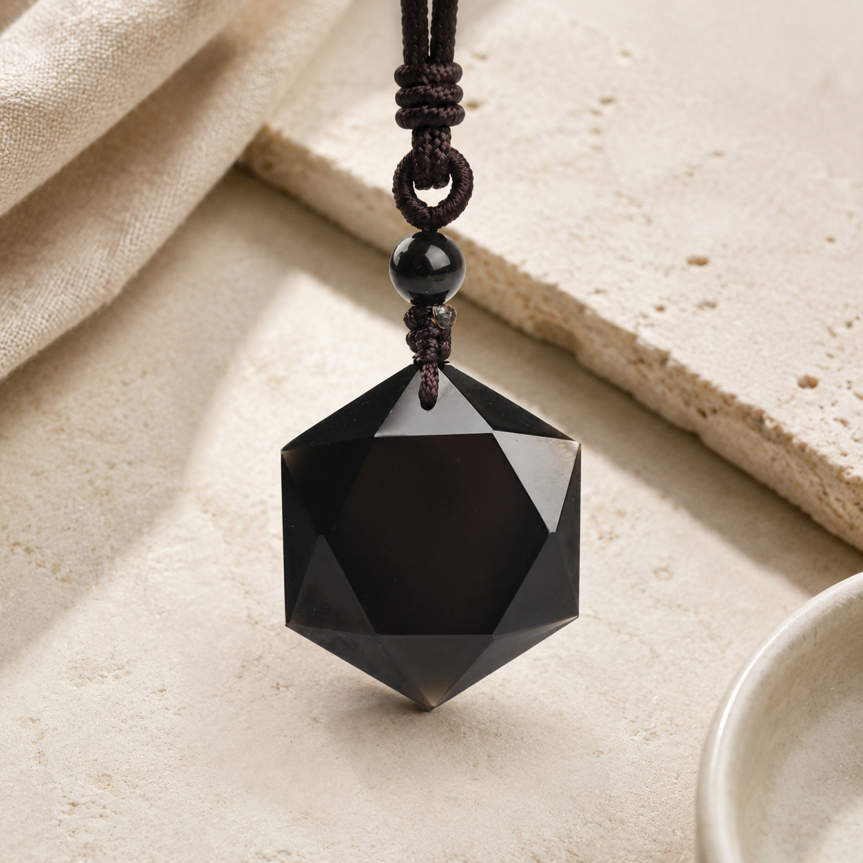 Obsidian Six-Pointed Star Pendant Necklace on warm ivory stone.