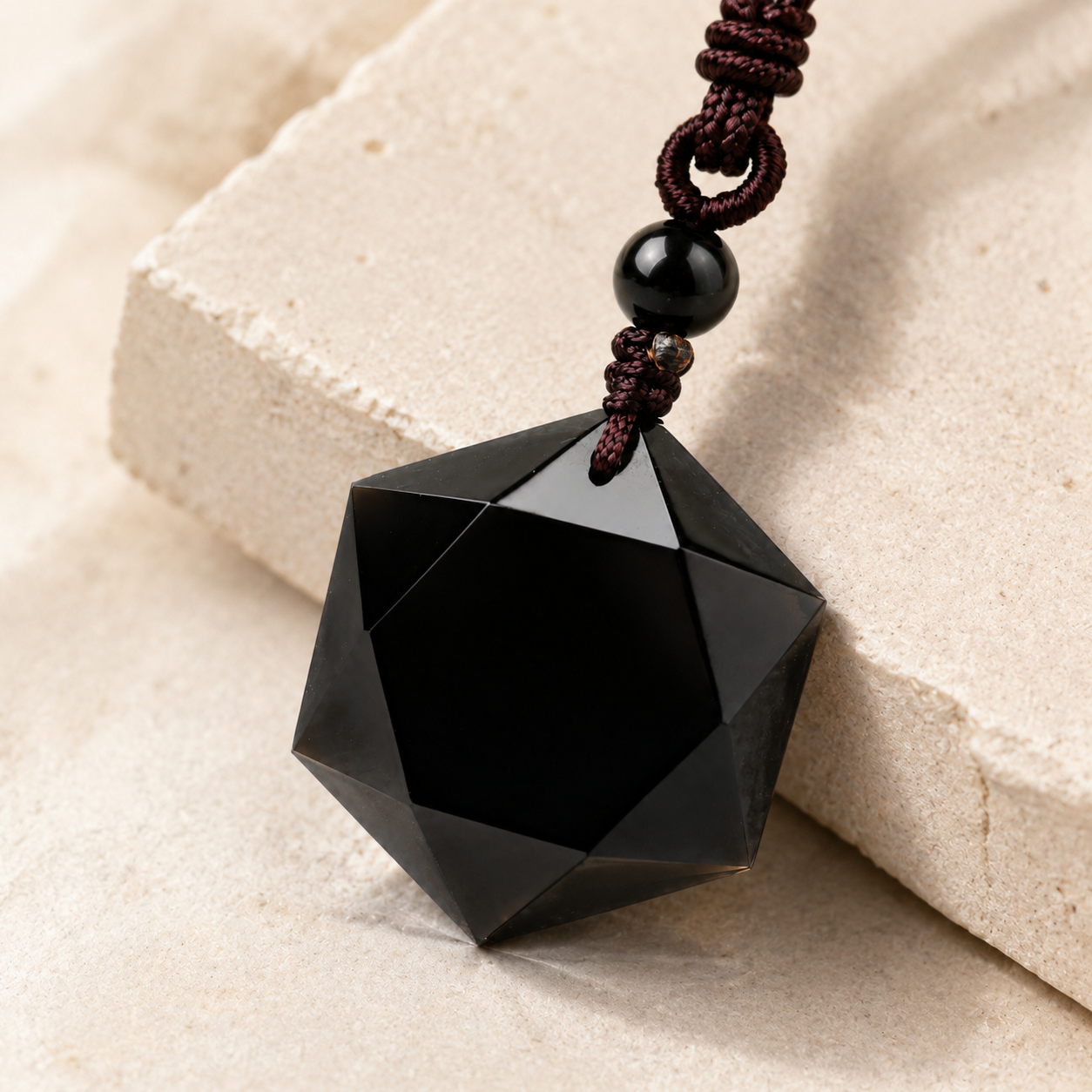 Black obsidian six-pointed pendant on a coffee-toned cord.