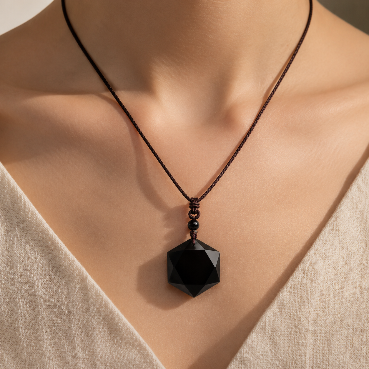 Obsidian pendant necklace worn at the neckline.