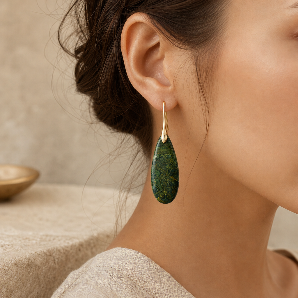 Gold green natural stone waterdrop earrings shown in an ear-level lifestyle crop.